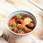 Thai Tom Yum Soup, Thai Soup with Shrimp and Mushroom, Coconut Milk, and Curry. Top View on Wooden Table